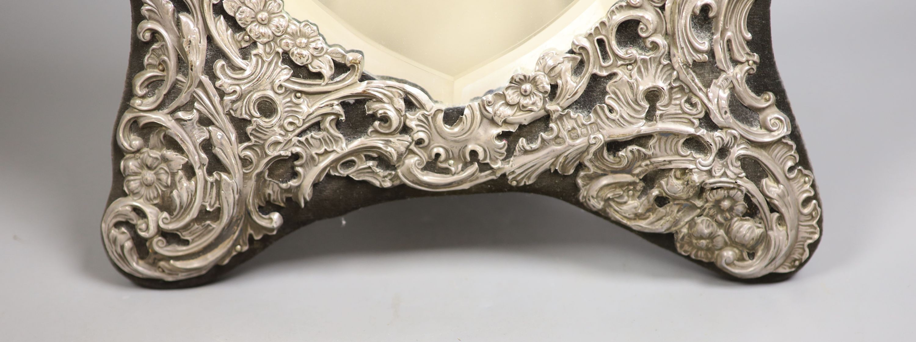 An Edwardian repousse silver mounted easel mirror, with heart shaped plate, William Comyns, London, 1906, 36cm.